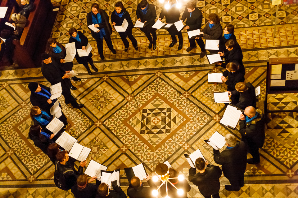 Der Chor ist aus der Vogelperspektive zu sehen. Die Sängerinnen und Sänger stehen im Kreis. Sie stehen auf dem kunstvollen Mosaikboden des Stephansdoms in Wien.